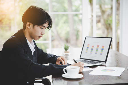 Close up of asian businessman surfing the internet, searching information on laptop computer and digital tablet pc, online working from home office, telecommuting. Freelancer working on computerの写真素材