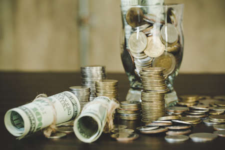 Saving money by dollars with coins in jug glass on dark backgroundの写真素材
