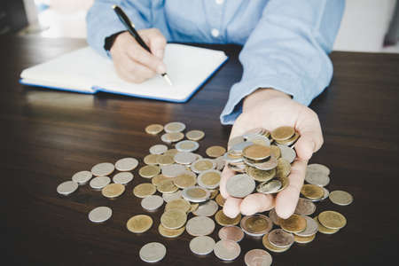 a woman makes calculations, checks her finances, makes notes in a notebook and sets aside some of...