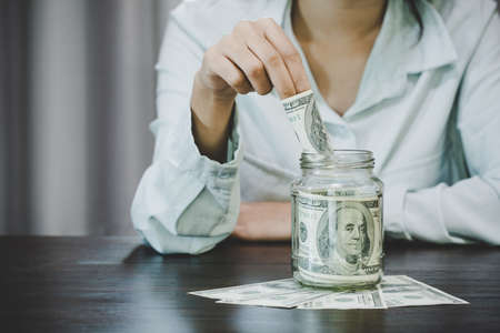 Woman holding dollar bills,  she is managing to divide the money to save money and invest it to make it grow even more. Saving money and investing concept.の写真素材