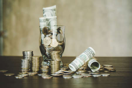 Saving money by dollars with coins in jug glass on dark backgroundの写真素材
