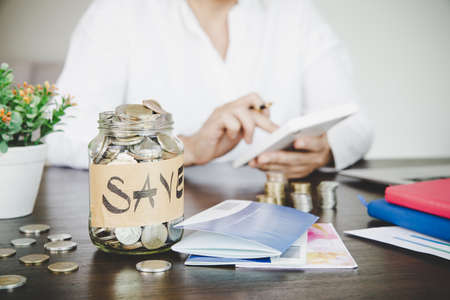 a woman makes calculations, checks her finances, makes notes in a notebook and sets aside some of the fundsの写真素材