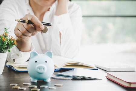 woman hand putting money into piggy for saving money wealth and financial concept.の写真素材