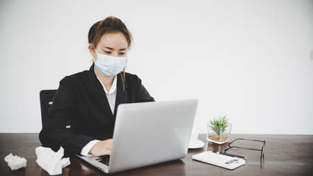 Sick young asian business woman wearing protective face mask having cold fever.Health problems conceptの写真素材