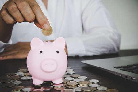 woman hand putting money into piggy for saving money wealth and financial concept.の写真素材