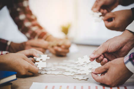 Business people and puzzle on wooden table, teamwork conceptの写真素材