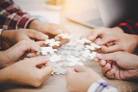 Business people and puzzle on wooden table, teamwork conceptの写真素材