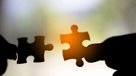 Closeup hand of woman connecting jigsaw puzzle with sunlight effect, Business solutions, success and strategy conceptの写真素材