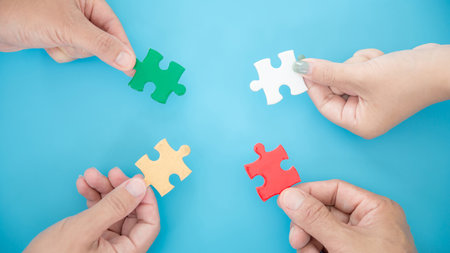 High Angle View Of Businesspeople Hand Solving Jigsaw Puzzle On Blue Backgroundの写真素材