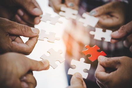 Hands holding piece of blank jigsaw puzzle for teamwork workplace success and strategy concept.の写真素材