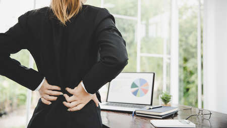 Young business woman at the office with terrible back pain while she is working in the office .Health problems conceptの写真素材