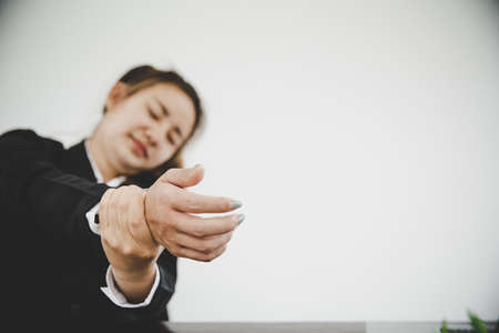 Young asian business woman sitting on the chair twisted relieve fatigue  while she is sitting in the office workingの写真素材