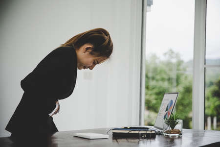 young business woman suffering from stomach pain  while she is working in the office  .Health problems conceptの写真素材