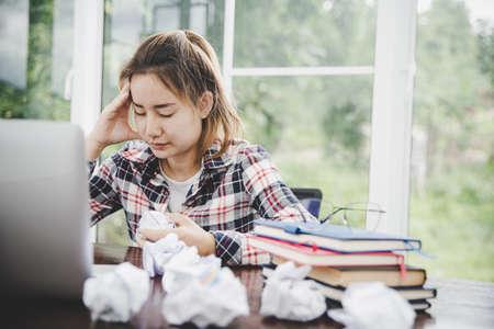 woman sitting down, his face unsettled. At the computer desk she has headaches and stress. Cause of hard work and insufficient rest.の写真素材