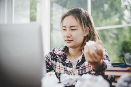 woman sitting down, his face unsettled. At the computer desk she has headaches and stress. Cause of hard work and insufficient rest.の写真素材
