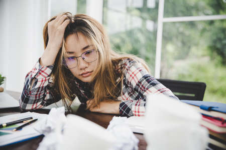 Young frustrated woman working at office desk in front of laptop suffering from chronic daily headaches, treatment online, appointing to a medical consultation, electromagnetic radiation, sick payの写真素材