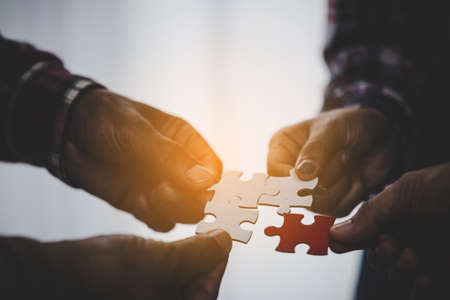 Hands holding piece of blank jigsaw puzzle for teamwork workplace success and strategy concept.の写真素材