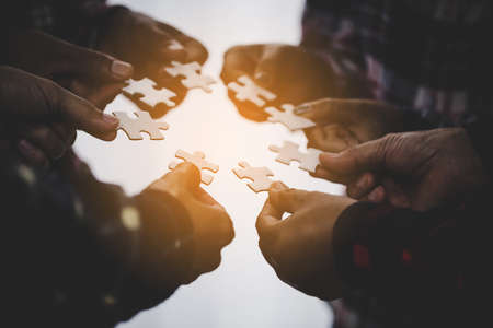 Hands holding piece of blank jigsaw puzzle for teamwork workplace success and strategy concept.の写真素材