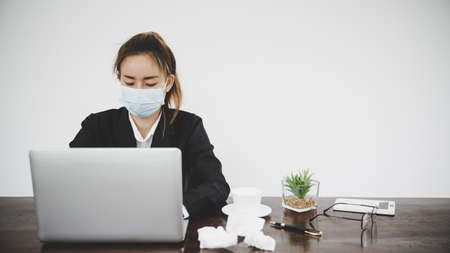 Sick young asian business woman wearing protective face mask having cold fever.Health problems conceptの写真素材