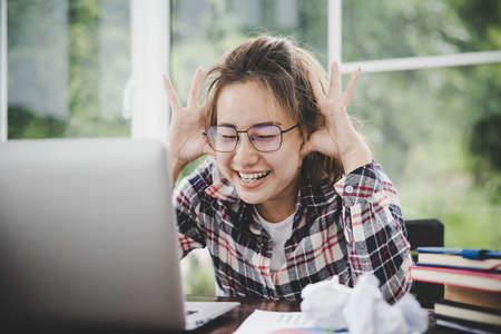 Young frustrated woman working at office desk in front of laptop suffering from chronic daily headaches, treatment online, appointing to a medical consultation, electromagnetic radiation, sick payの写真素材