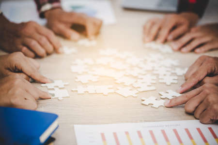 Business people and puzzle on wooden table, teamwork conceptの写真素材