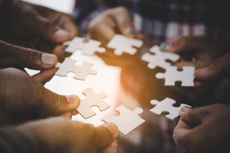 Hands holding piece of blank jigsaw puzzle for teamwork workplace success and strategy concept.の写真素材