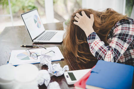 Young frustrated exhausted woman laid her head down on the table sit work at white desk with contemporary  laptop isolated. Achievement business career concept. Copy spaceの写真素材