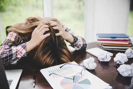 Young frustrated exhausted woman laid her head down on the table sit work at white desk with contemporary  laptop isolated. Achievement business career concept. Copy spaceの写真素材