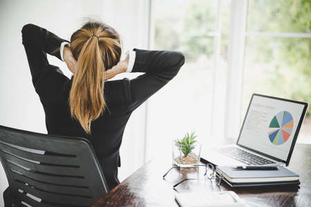 Young asian woman is sitting at work and has pain in her neck while she is sitting in the office workingの写真素材