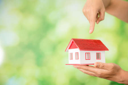 Small model house against green bokeh background. building, loan, real estate or buying a new home concept.の写真素材