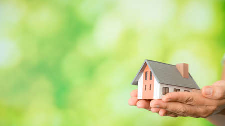 Small model house against green bokeh background. building, loan, real estate or buying a new home concept.の写真素材