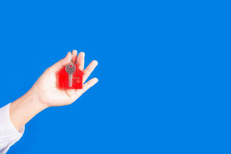 Woman hand holding key house on blue backgroundの写真素材