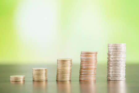 Deposit coins as an investment concept. It is growing to make rich and wealth. It is on table in front of golden bokeh background. Accumulate or income concept.の写真素材
