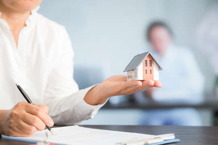 Businesswoman choosing mini house model from model on wood table, Planning to buy property. concept of Choose the best.の写真素材
