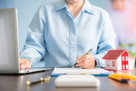 Businesswoman choosing mini house model from model on wood table, Planning to buy property. concept of Choose the best.の写真素材