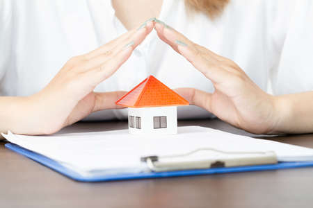 young woman use two hand to protect house model. real estate, insurance and property conceptsの写真素材