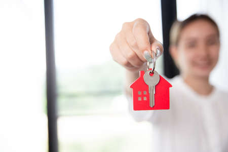 Close up portrait of smiling asian woman hold show keys to new house. estate and property conceptの写真素材