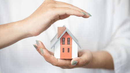 Hands of a woman surround a house model. real estate, insurance and property conceptsの写真素材