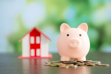 Model house with piggy bank and coins money on natural green background, Business investment and real estate conceptの写真素材