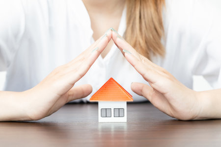 young woman use two hand to protect house model. real estate, insurance and property conceptsの写真素材