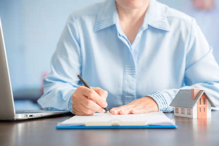 Businesswoman choosing mini house model from model on wood table, Planning to buy property. concept of Choose the best.の写真素材