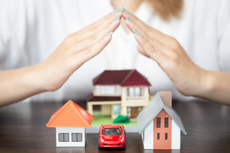 young woman use two hand to protect house model and toy car. real estate, insurance and property conceptsの写真素材