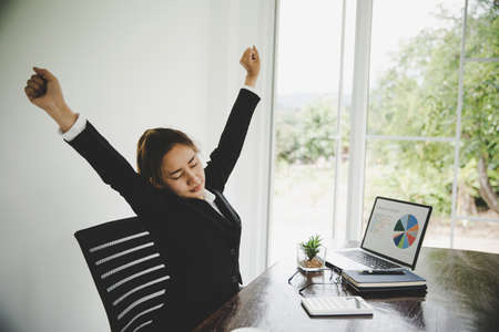 Young asian business woman sitting on the chair twisted relieve fatigue  while she is sitting in the office workingの写真素材