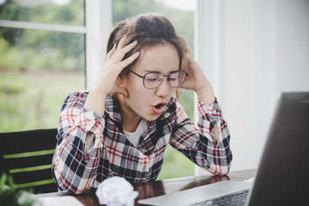 Emotional business lady shouting at her laptop. Hard stressful workday in the officeの写真素材