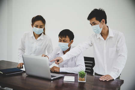 Group business people communicate working with laptop in office in masks during  pandemicの写真素材