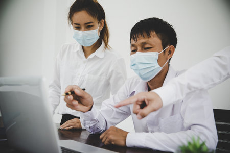 Group business people communicate working with laptop in office in masks during  pandemicの写真素材