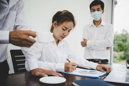 Group business people have a meeting businessman wearing mask and businesswoman not wearing mask working in a officeの写真素材