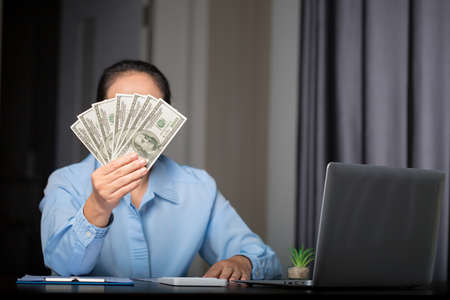 Close up young business woman using counting cash money one hundred dollar bills, checking financial documents, sitting at table with papers and tax form, managing planning budget, accounting expensesの写真素材