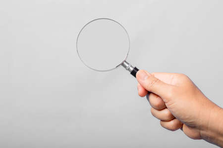 woman hand holding magnifying glass isolated on gray background. optical zoom lens is macro tool, concept for education, science.の写真素材