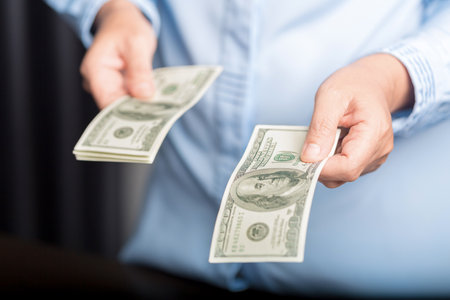 business woman hand giving one hundred dollar bills, close-up of a hand counting paper dollars. Concept for salary, loan, credit.の写真素材